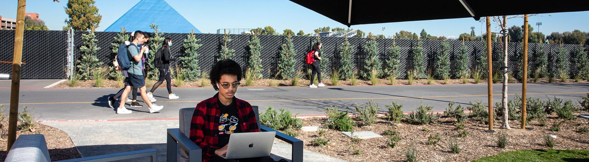 Student works on a computer outside on campus