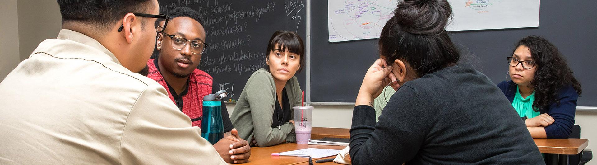 Five students sitting around a classroom table