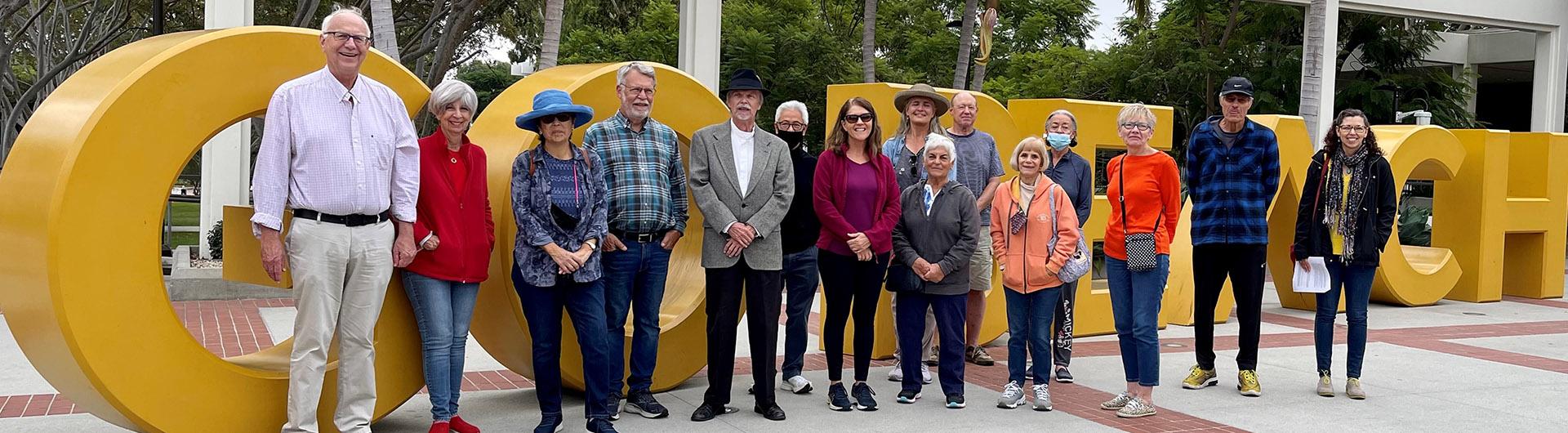 Group of OLLI members standing in front of GO Beach letters