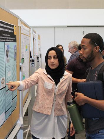 student presenting research poster to fellow student