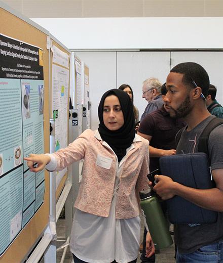 student presenting research poster to fellow student