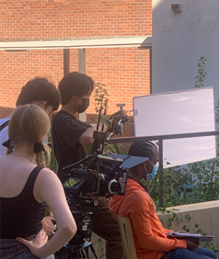 students filmming on campus with camera