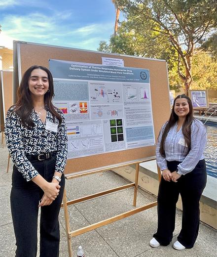two chemistry students standing proudly in front of their poster presentation
