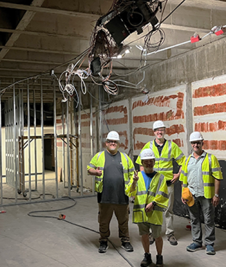 Film & Electronic Arts Staff standing with hard hats during construction of building.