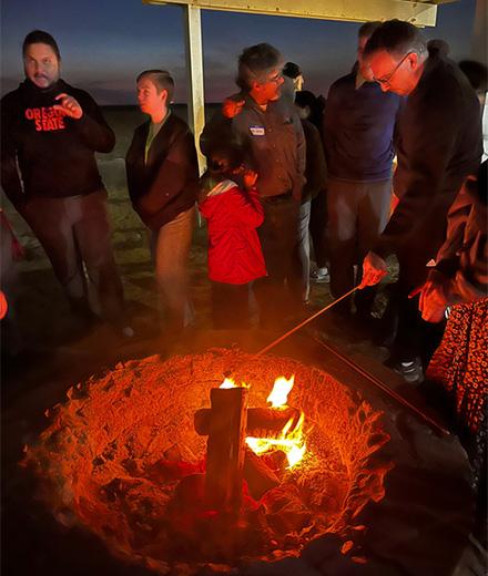 people talking around a beach firepit at night