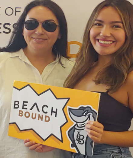 Two girls with Sign Beach Bound ant CSULB College of Business