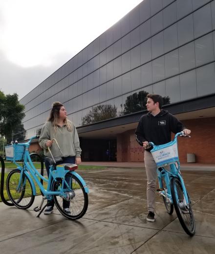 Two students riding on bike share bikes
