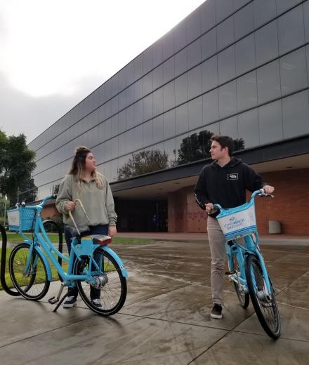 Two students riding on bike share bikes