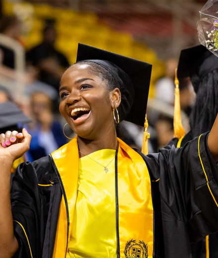 Black Graduate during the Black Cultural Grad Ceremony cheering and holding flowers