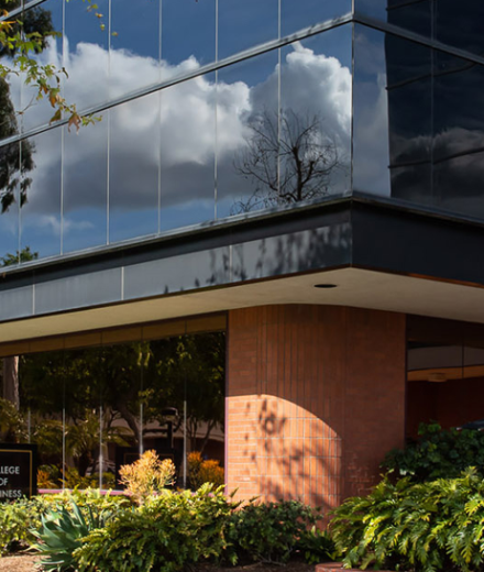 Exterior Shot of the College of Business building, featuring black mirrored windows and green landscaping below.