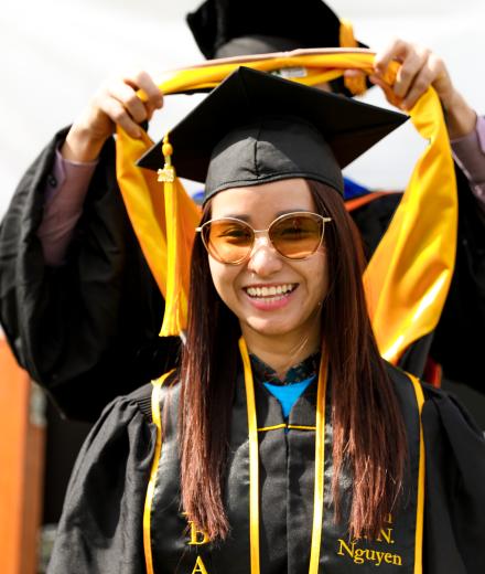 Photo of a female graduation during her hooding ceremony with a professor placing the hood on her 