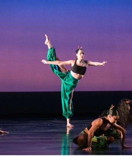 A dancer dances on stage with other performers.