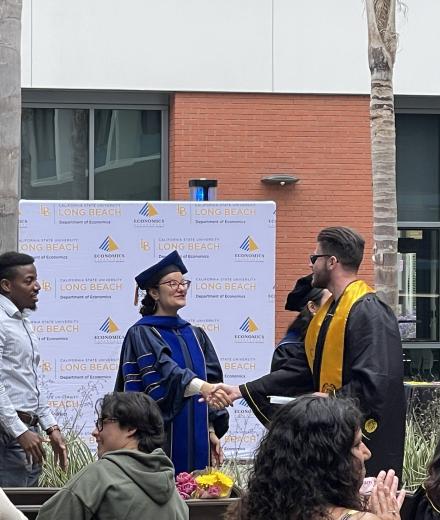 Dr. Mileva congratulating graduating students in the progression in front of families and friends.