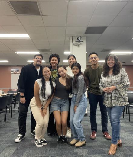 group of seven students huddled for a photo in the Anatol Center for the amplifying student voices column