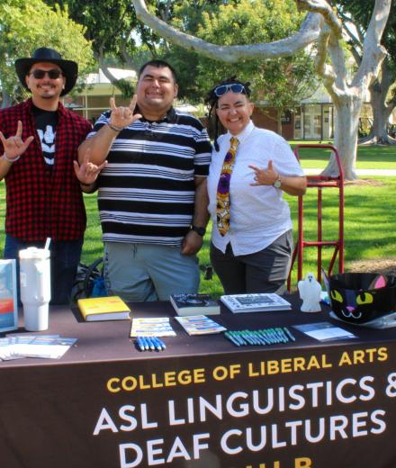 three people signing at the ASL and Deaf Cultures outreach table at CLA day