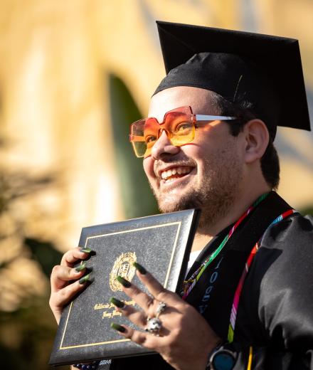 College of the Arts Graduate holding up their diploma