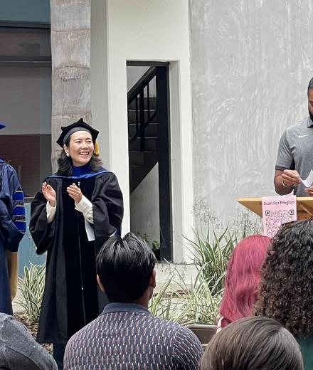 Photograph of a graduating student walking during the procession in front of the faculty, family, and friends. 