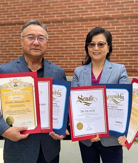 Kensaku Nakayama and Lijuan Li holding multiple award certificates