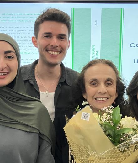 students posing with faculty member and flowers