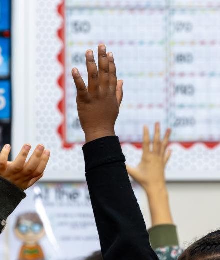 First grade students hold up their hands in a class at Mark Twain Elementary