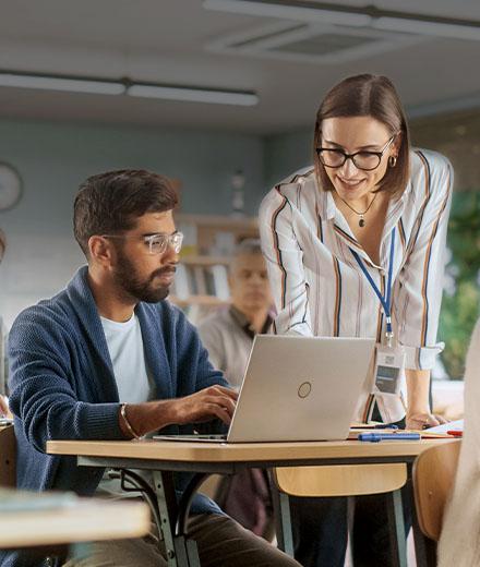 Woman teaching male student with laptop