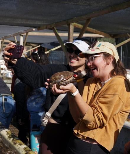 two people holding an abalone and taking a photo