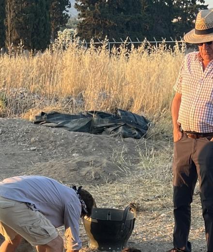 archaeologists looking at a pit in the field