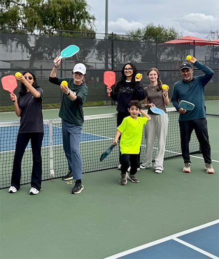 people posing in a pickleball serve pose