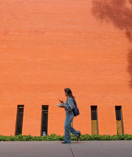a student walking in front of a brick building