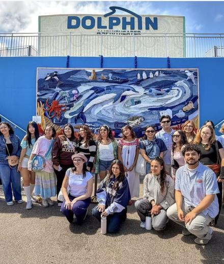 Group poses in front of SeaWorld mural