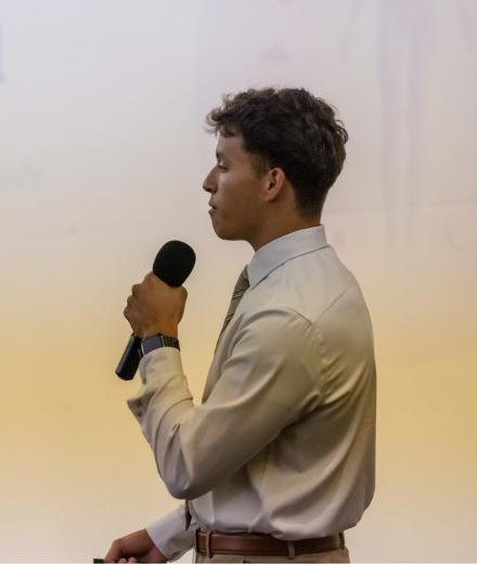 man presenting on stage in front of a screen