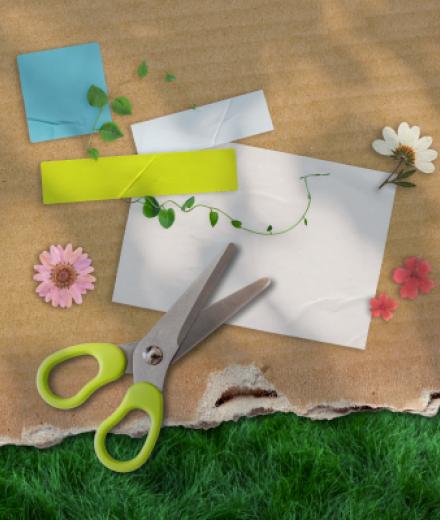 A cardboard background with a pair of scissors and flowers