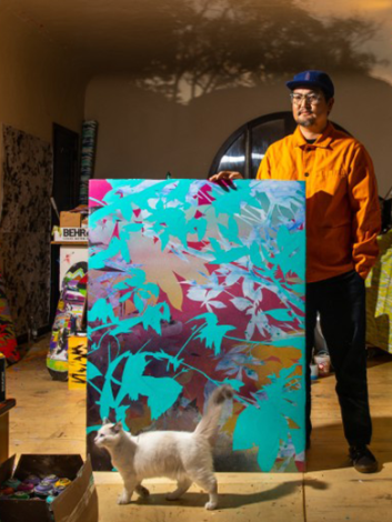 Artist Devin Tsuno standing in front of a painting