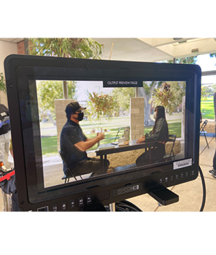 two students sitting on table viewed through monitor