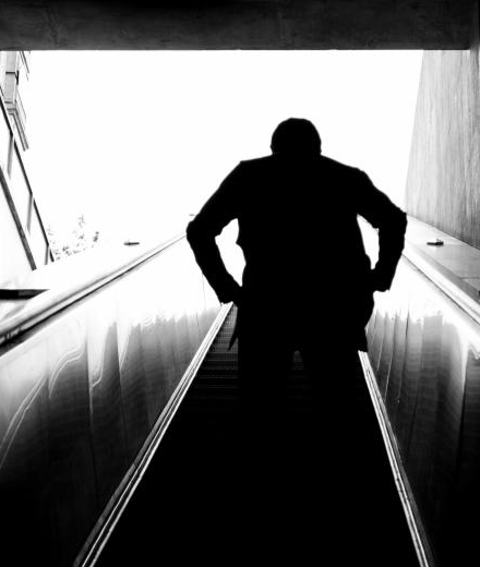 Man riding an escalator up out of a Paris Underground station