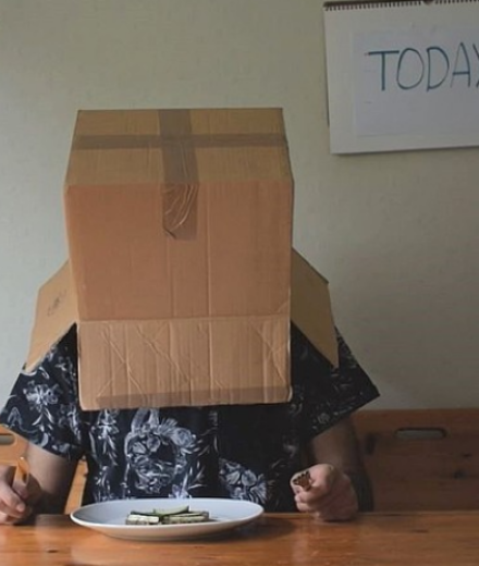 Person with box over head and "today" sign on wall