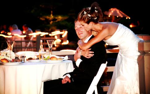 The bride kissing the grooms cheek at the bride and groom table.