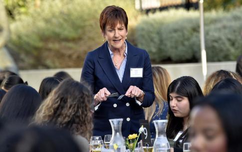 Alumna Diane shows students how to use knife and fork 