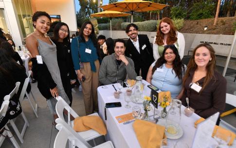 Students and alumni pose for a group photo around the dinner table