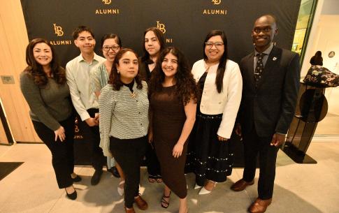 Students pose for a group photo with the CSULB Alumni step and repeat