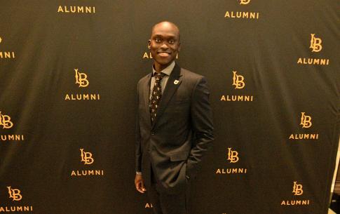 Student poses for a photo with the CSULB Alumni step and repeat
