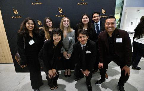 Students and alumni pose for a group photo with the CSULB Alumni step and repeat