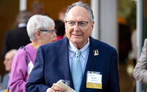 Man with gray hair holding glass drink