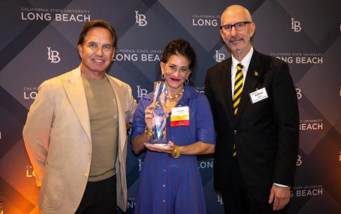 Awardee holding award next to two men