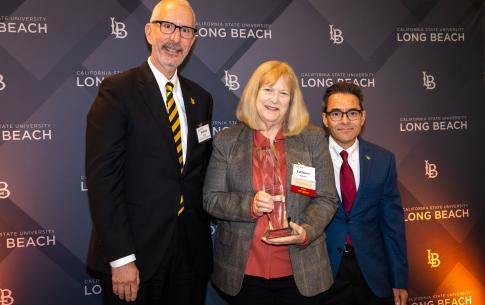 Awardee holding award next to two men