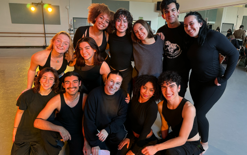 MJ Wolff with eleven dancers pose in a Dance Center studio.