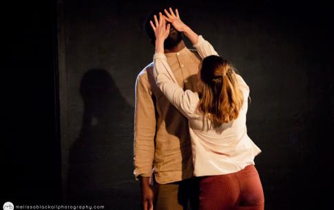 T and another dancer perform on stage. A female dancer reaches out to cover his eyes.