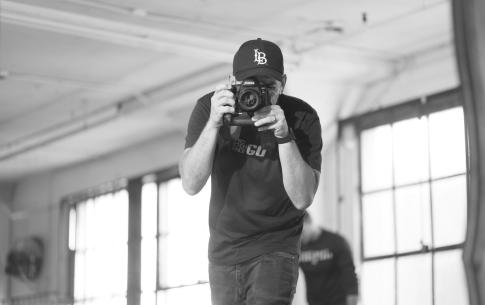 Black and white self portrait of Gregory R.R. Crosby in a LB baseball cap