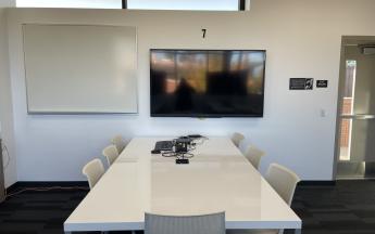 workspace with desk, chairs, whiteboard, and monitor