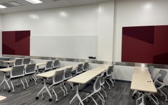 rows of tables with four chairs each on side of classroom